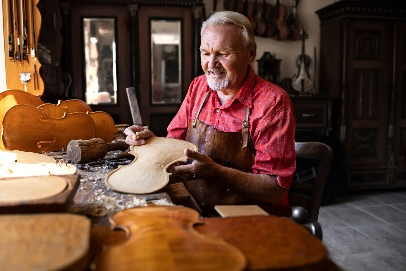 Professioneller, erfahrener Schreiner stellt eine hochwertige Violine für Studierende einer Musikakademie her.